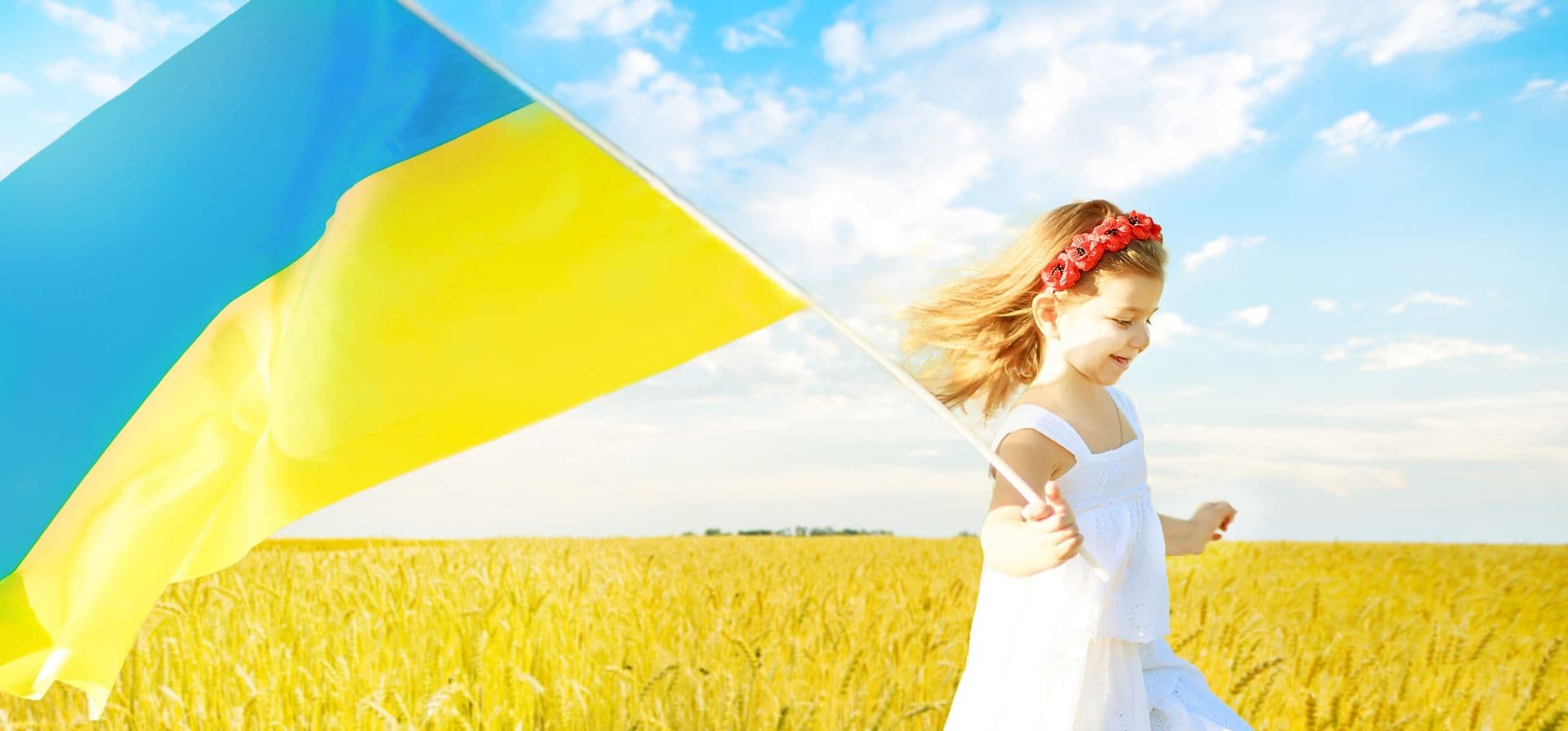 Girl running with the Ukrainian flag through a wheat field